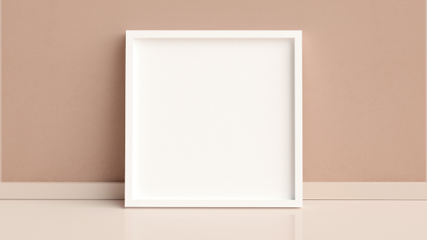 Moldura branca, em formato de quadrado, sobre uma superfície branca e encostada em uma parede marrom.
