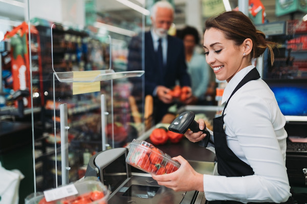 Mulher passando as compras de um senhor no supermercado como representação do setor terciário.