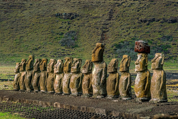 Vista de estátuas de moais enfileiradas na paisagem verde da Ilha de Páscoa.