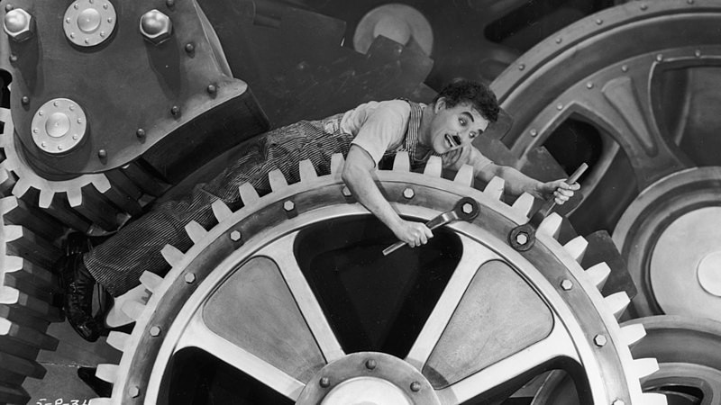 Charles Chaplin em cima de engrenagem, em cena do filme ?Tempos modernos?.