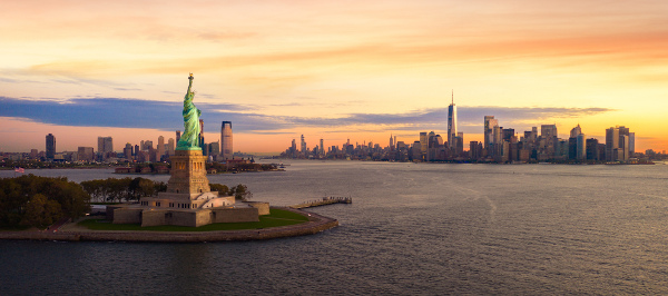 Estátua da Liberdade, ao pôr do Sol. Ao fundo, a ilha de Manhattan, NY, EUA.