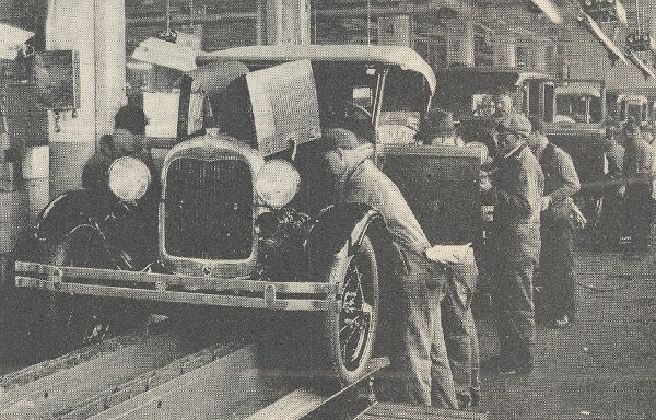 Operários em esteira de produção montando um carro, na ocasião do estabelecimento do fordismo como modelo industrial.