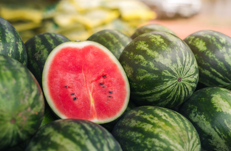 Melancias inteiras e uma cortada, alimentos ricos em nutrientes.