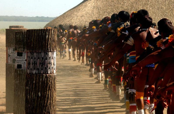 Dança ao redor de troncos que simbolizam os falecidos honrados no Quarup, uma celebração dos povos indígenas do Brasil.