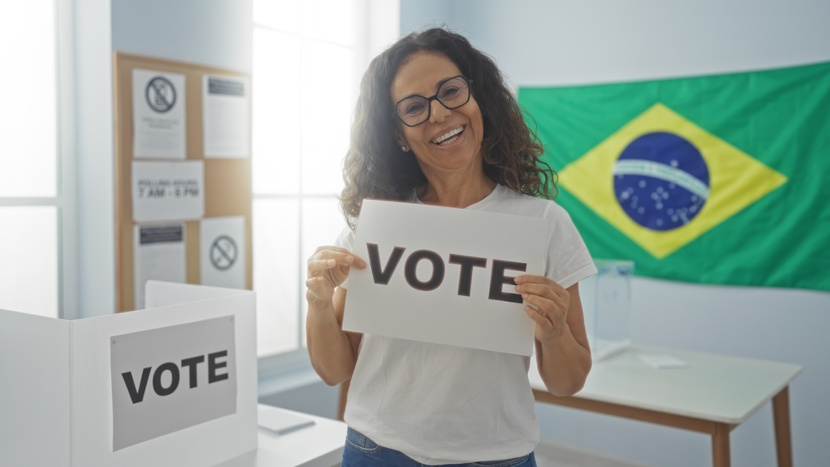 Mulher segura placa onde se lê “Vote” em referência a uma dos exemplos de cidadania: o voto.