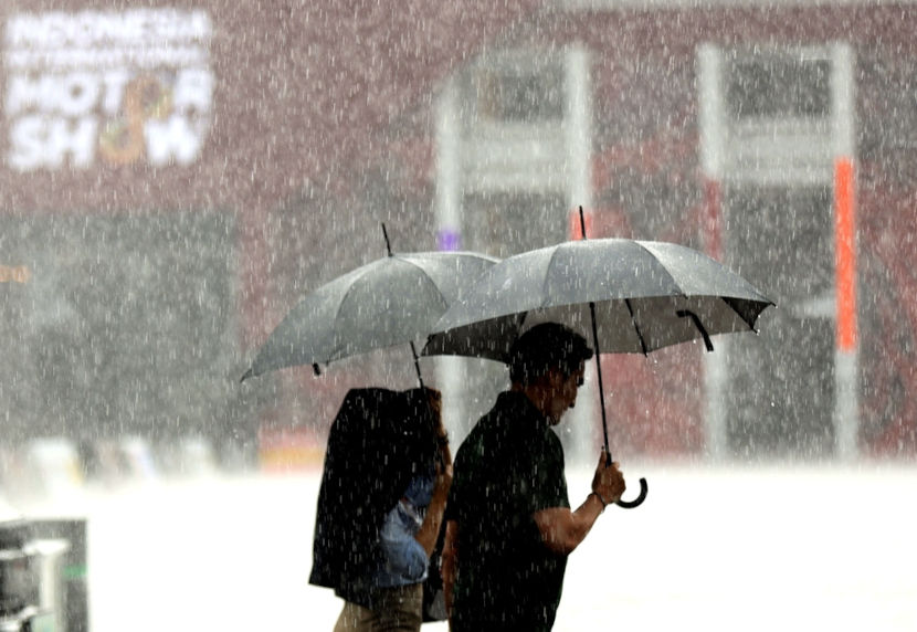 Pessoas usando guarda-chuva durante a chuva no clima tropical.